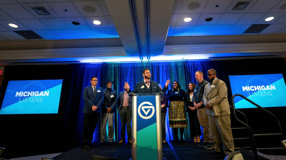 Kyle Kooyers, director of operations for the Kaufman Interfaith Institute, is pictured at the podium with the nine speakers who shared their stories during 'Michigan Listens' November 5 at the Eberhard Center.